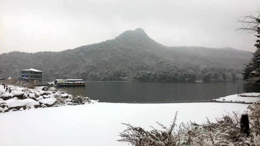 눈 덮인 산과 산정호수의 호숫가 풍경