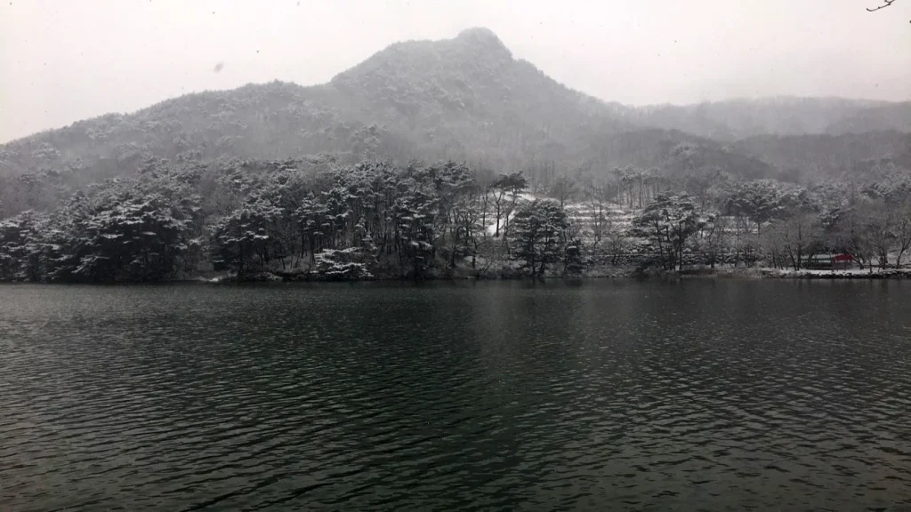 잔잔한 산정호수 건너편 눈 덮인 나무와 산