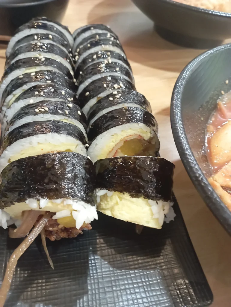 검은 접시에 두 줄로 놓인 먹기 좋게 썬 김밥
