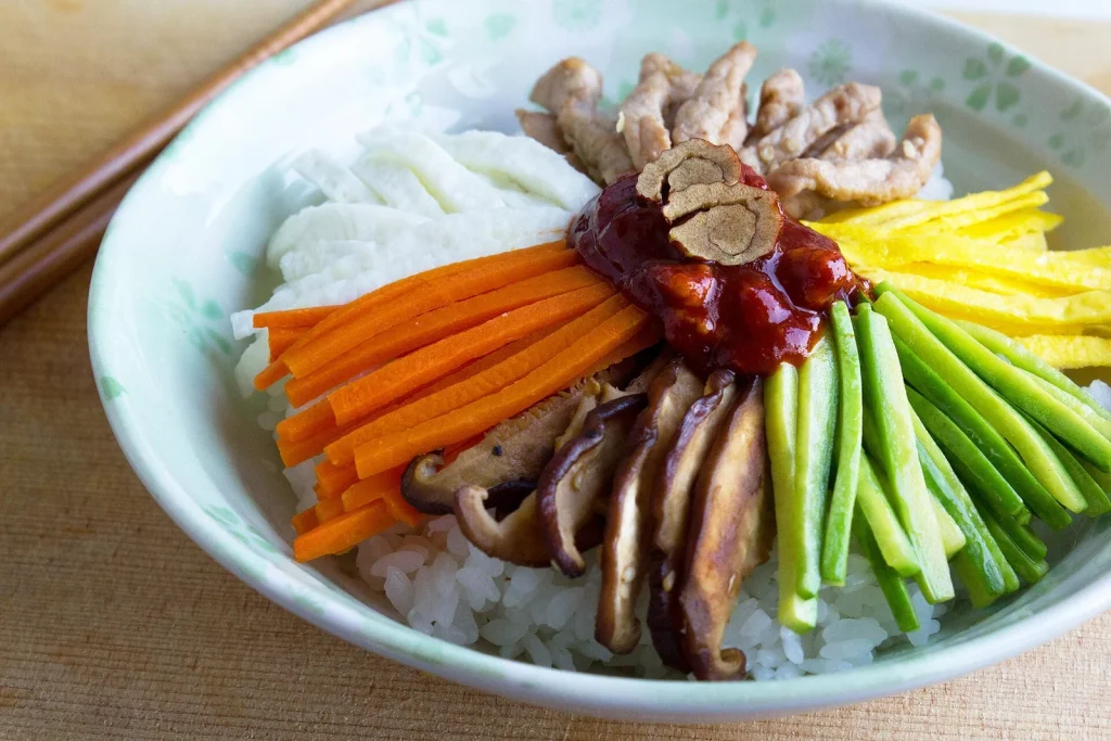 밥 위에 채소와 버섯, 양념을 담은 비빔밥 한 그릇